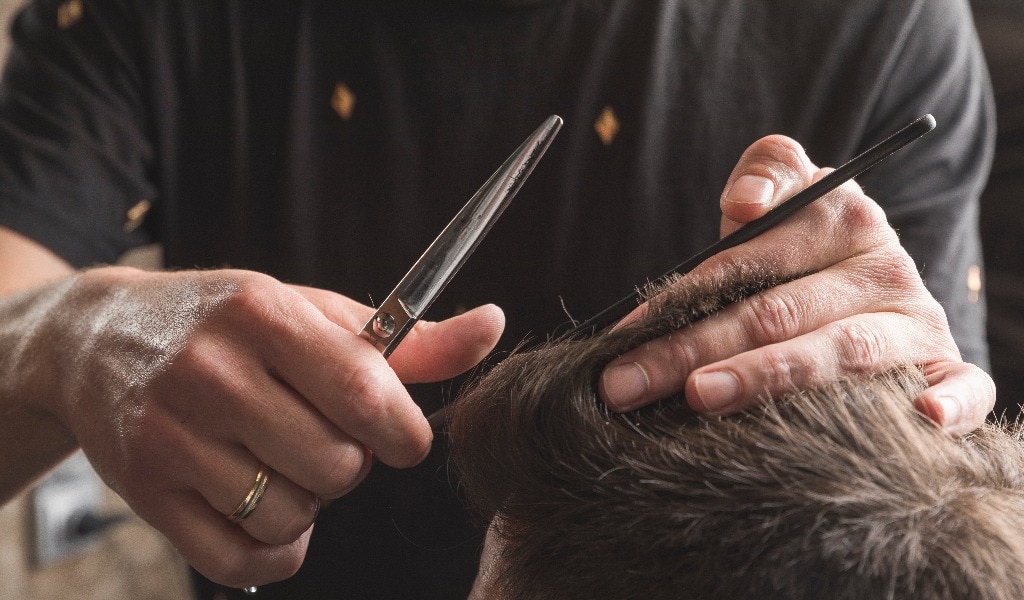 hombre peluquero cortando el pelo a cliente